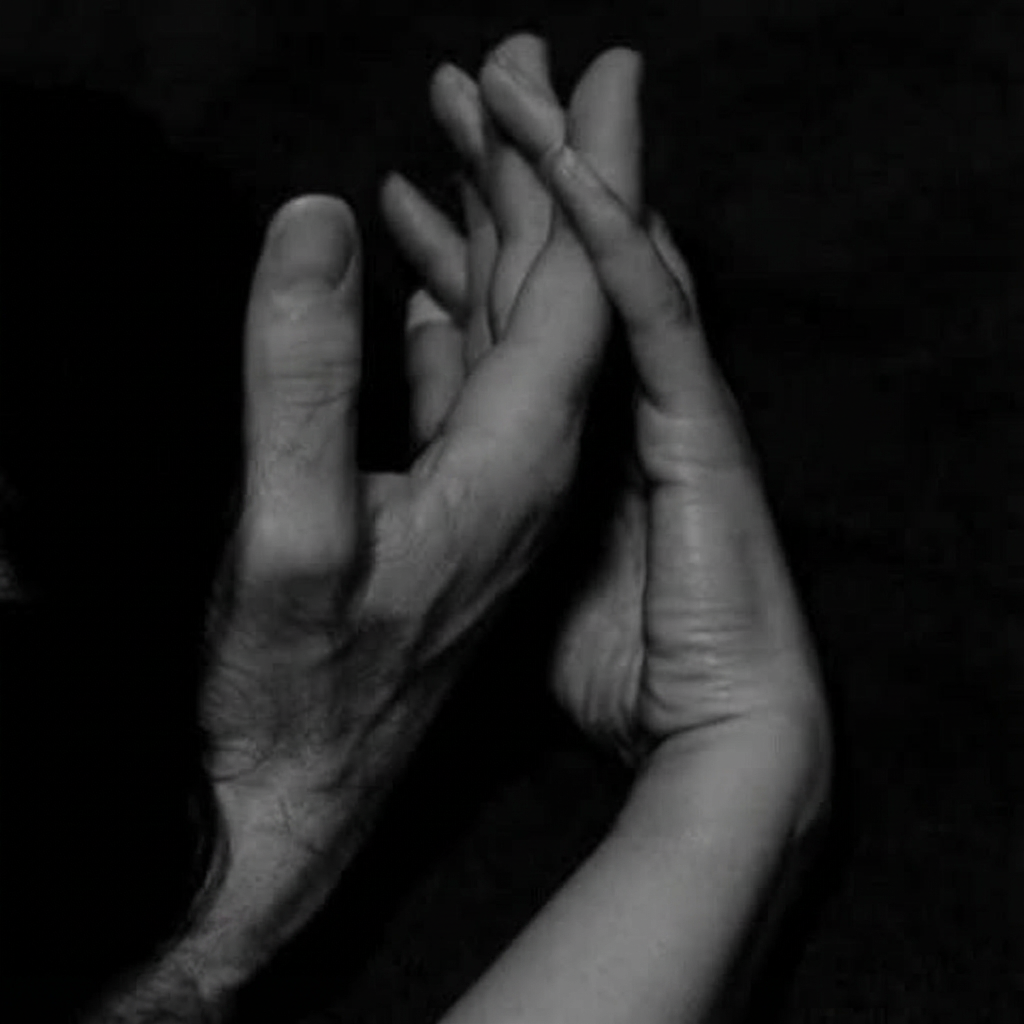 Twee handen die elkaar zacht aanraken tegen een donkere achtergrond, symbool voor intimiteit bij vaginisme