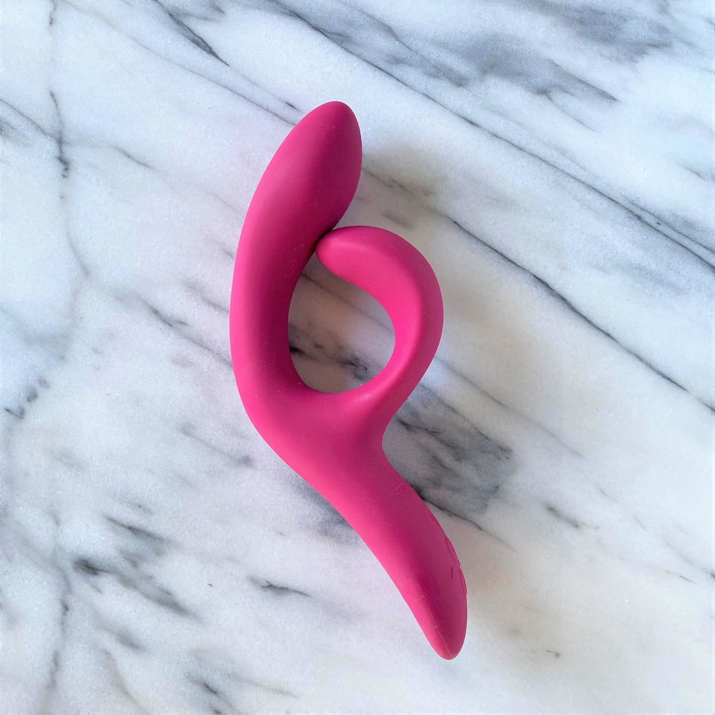 We-Vibe Nova 2 verpakking met roze-rode vibrator en bijgeleverde accessoires